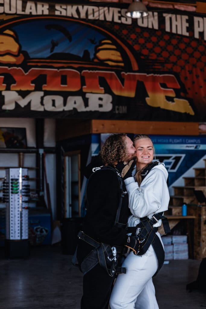 Excited couple laughing and celebrating together before boarding the plane for their tandem skydive during an adventurous elopement.