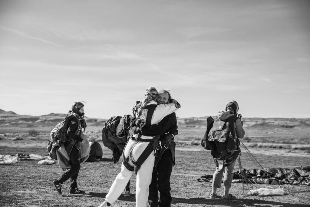 Couple hugging and celebrating after landing from their tandem skydive during their adventurous Moab elopement.