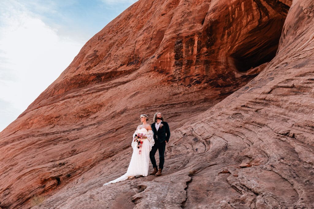 Eloping couple posing together on the red rock landscape during their adventurous Moab desert elopement.