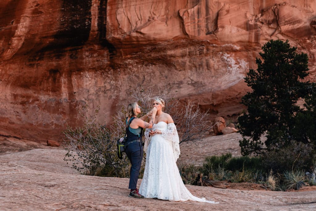 Makeup artist doing final touch-ups on the bride before the ceremony during a Corona Arch elopement in Moab.