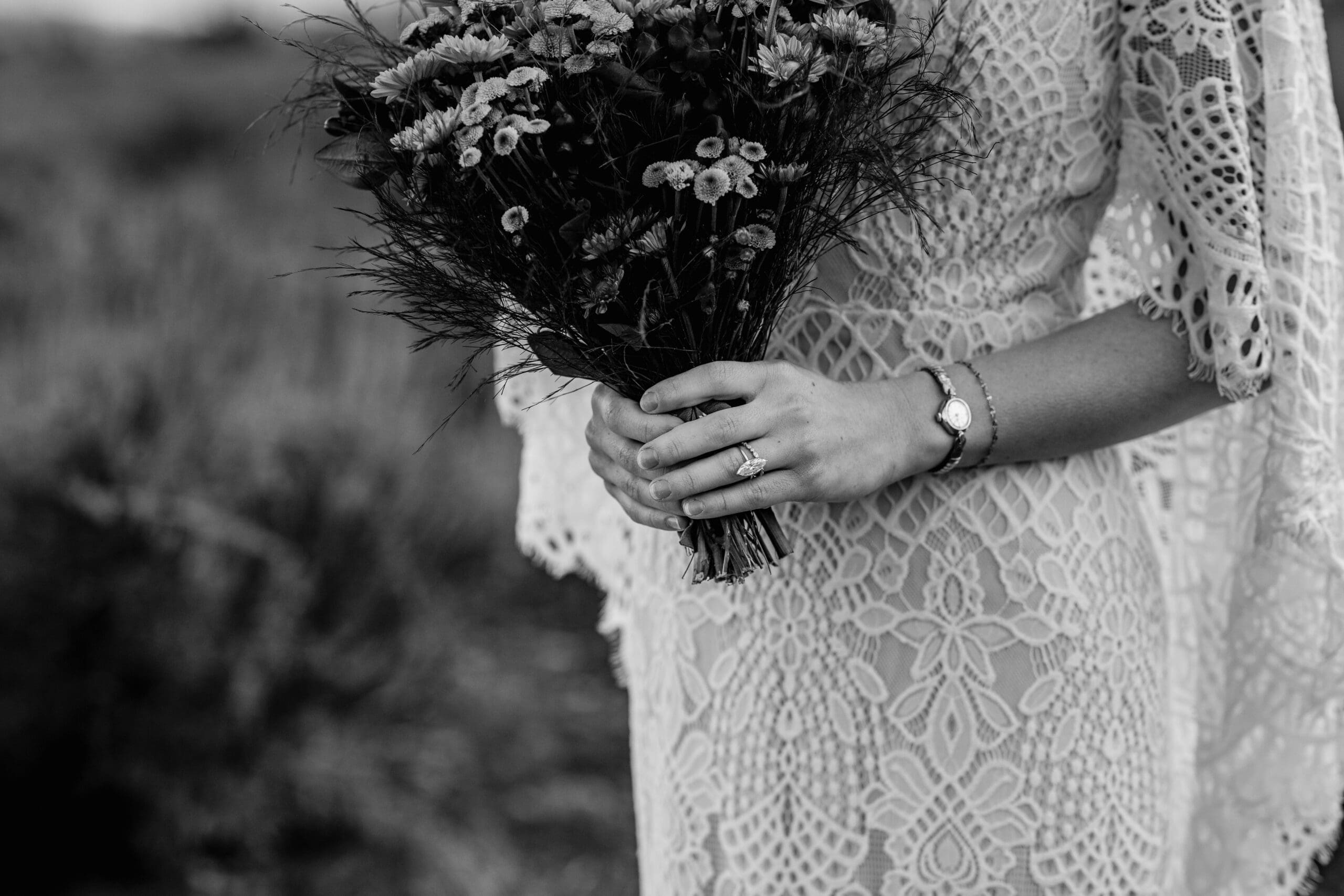 Black and white close-up of the bride’s bouquet and hands showing her engagement ring during an intimate elopement day.