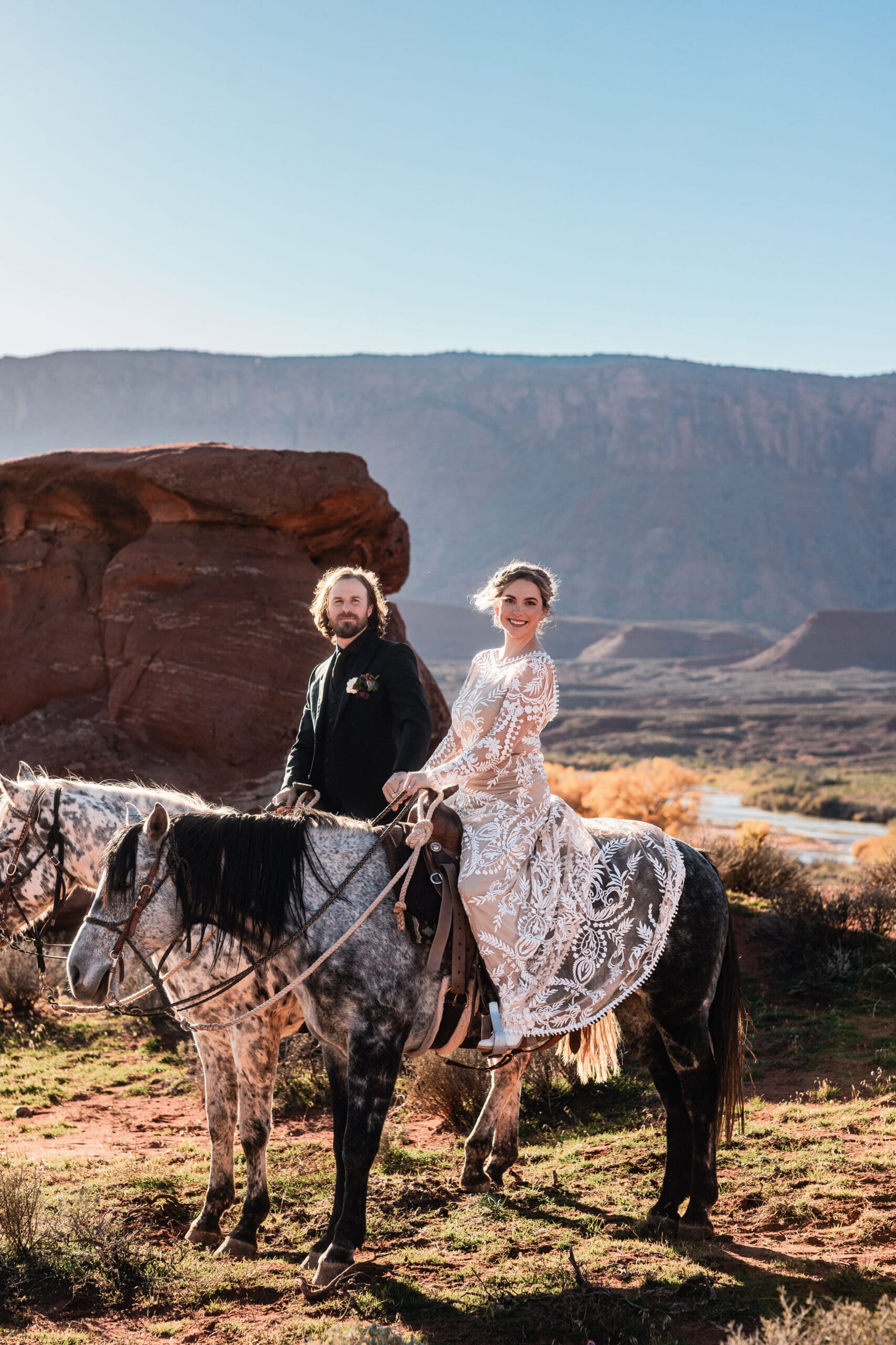 Eloping couple riding horses together at sunset at Hauer Ranch during their adventurous Moab elopement day.