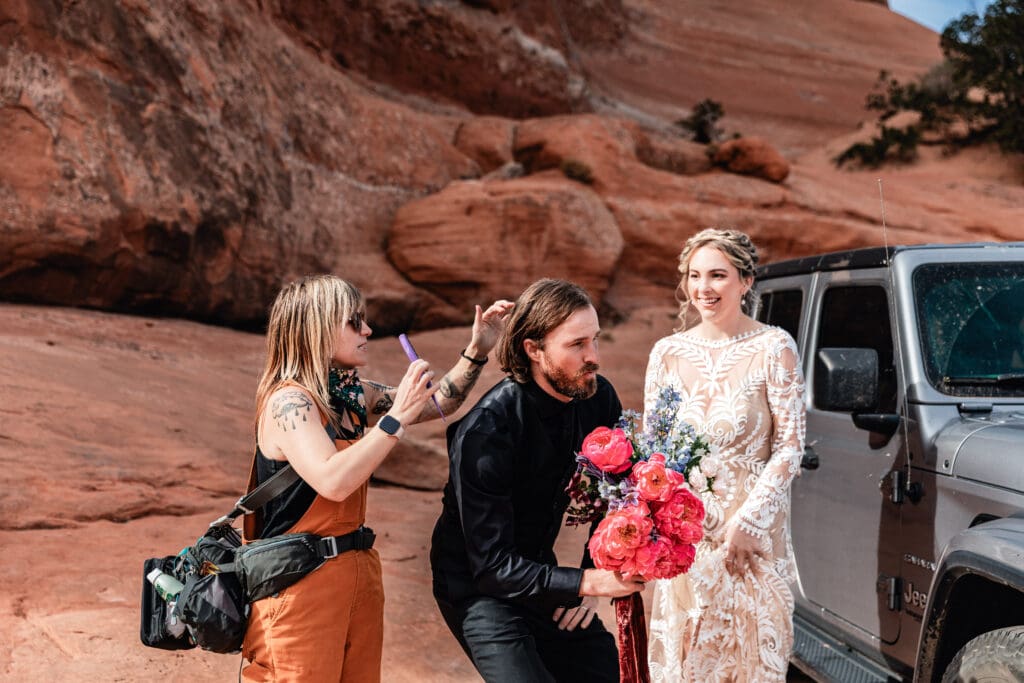 Hair stylist fixing the groom’s hair before the ceremony during a relaxed adventure elopement in the Moab desert.