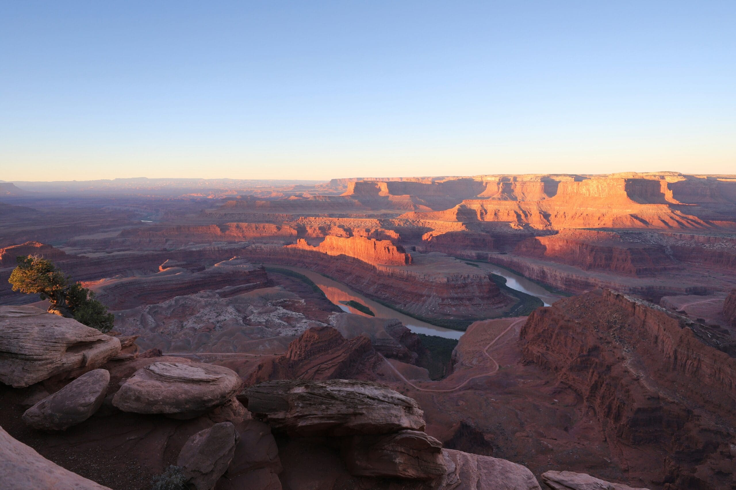 Dramatic cliffside view at Dead Horse Point State Park in Utah with deep canyon shadows, textured red rock formations, and soft evening light over the Moab desert